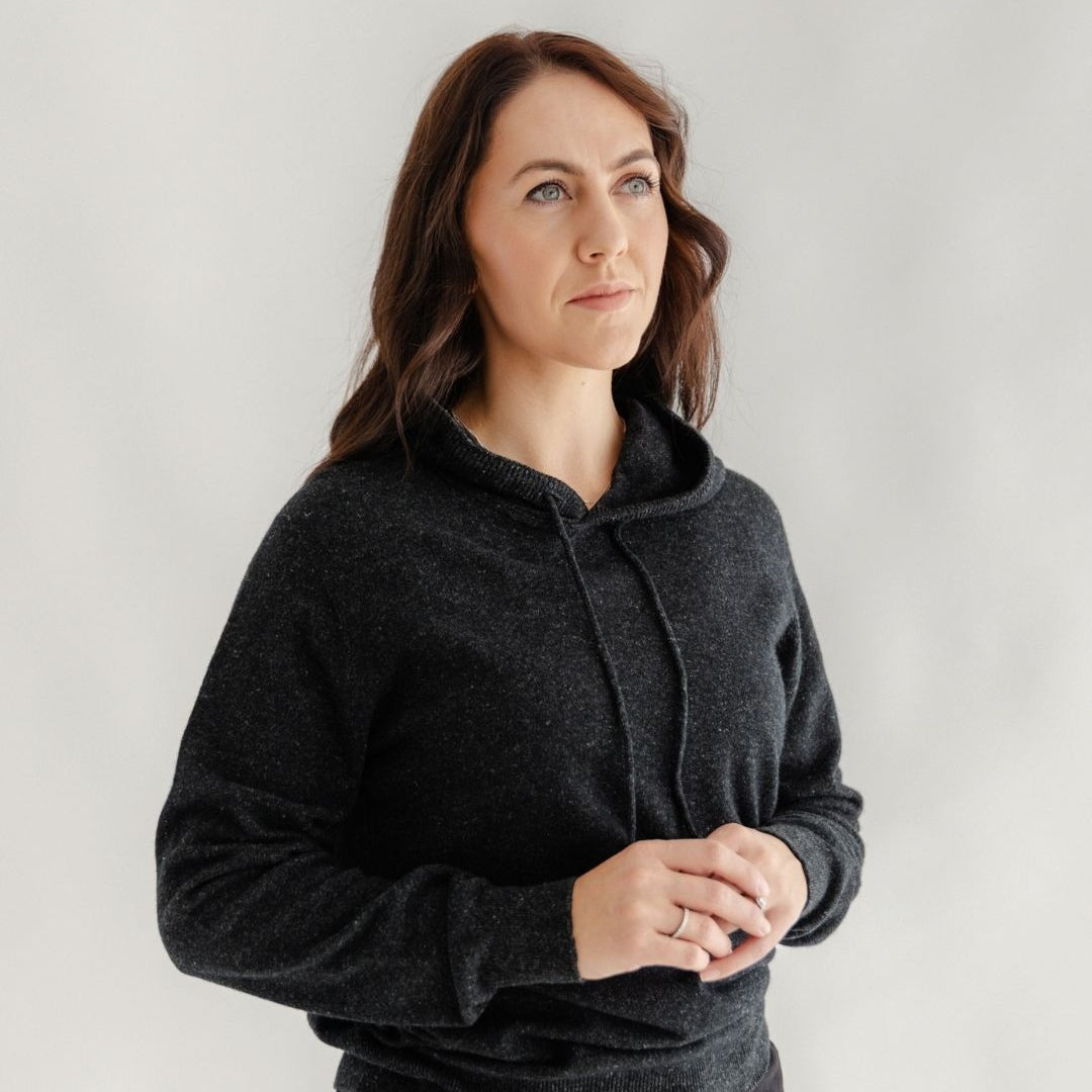 Woman wearing a dark gray hoodie against a plain background