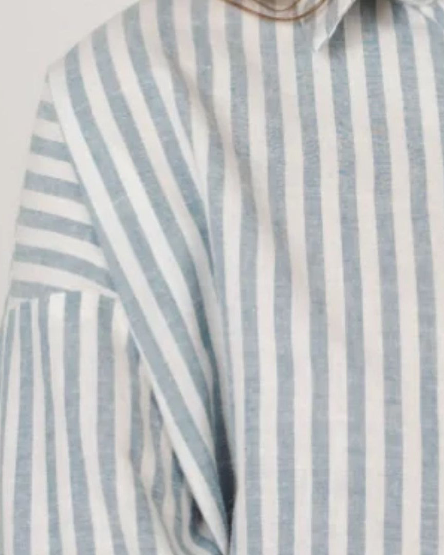 Striped shirt with blue and white vertical stripes on a light gray background