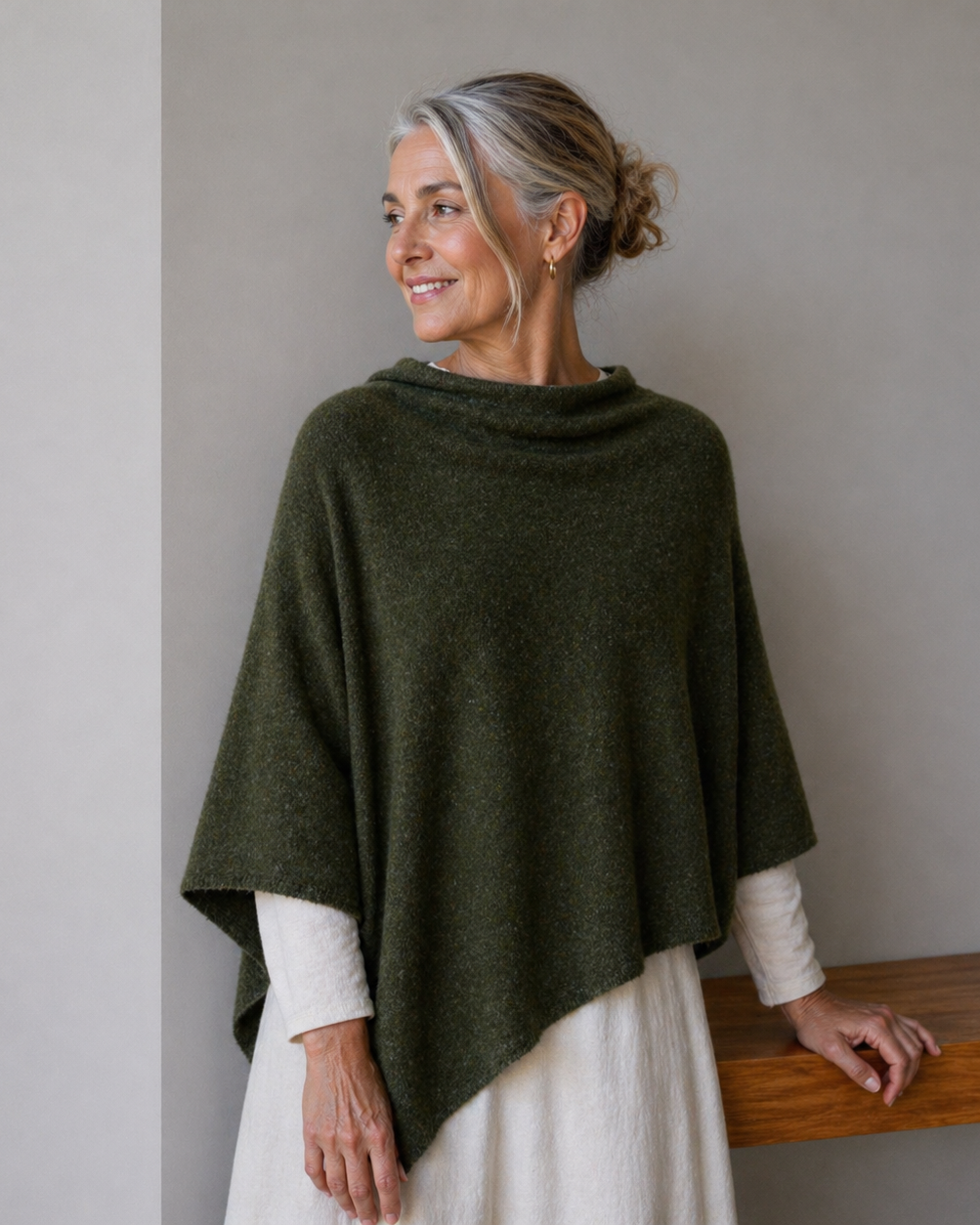 Woman wearing a green poncho against a plain background
