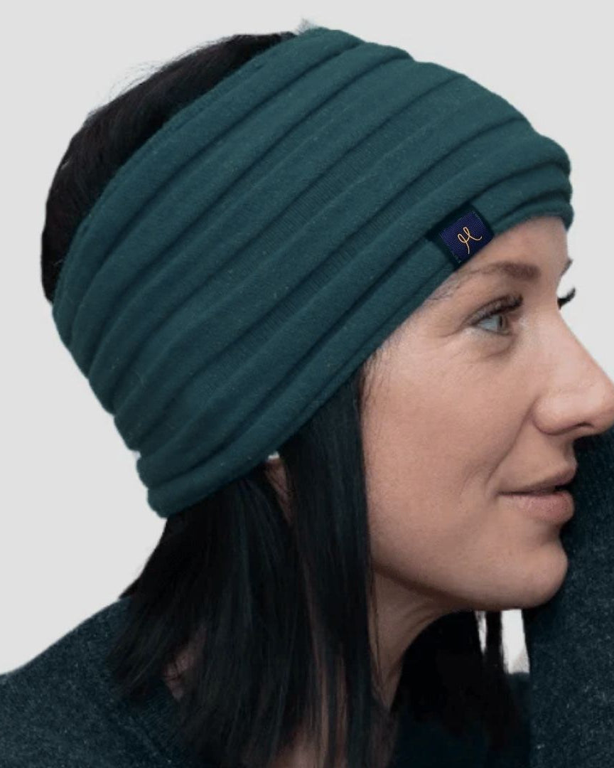 Woman wearing a teal headband with a brand logo on a light gray background