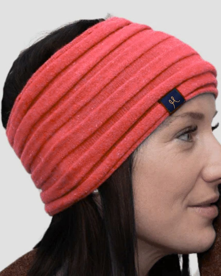 Woman wearing a pink headband with a brand logo on a plain background