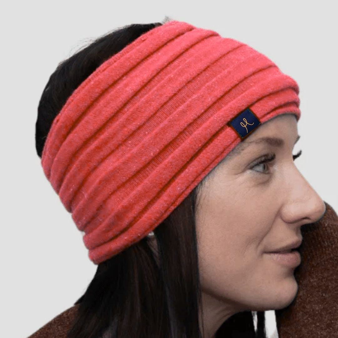 Woman wearing a pink headband with a brand logo on a plain background