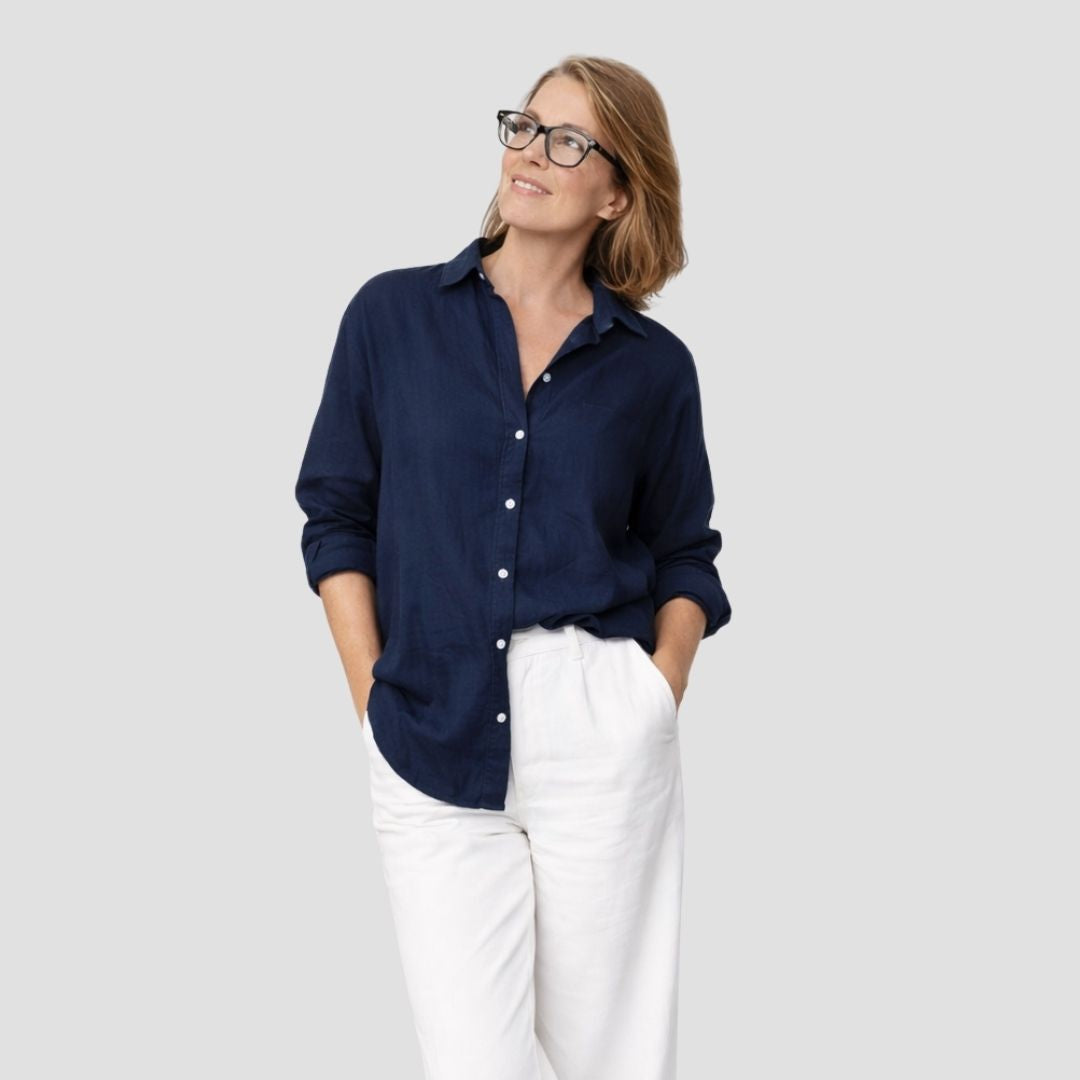 Woman wearing a navy blue shirt and white pants on a plain background