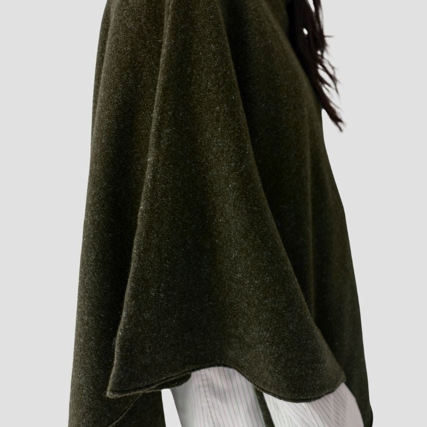 Dark green poncho over a white outfit on a light gray background