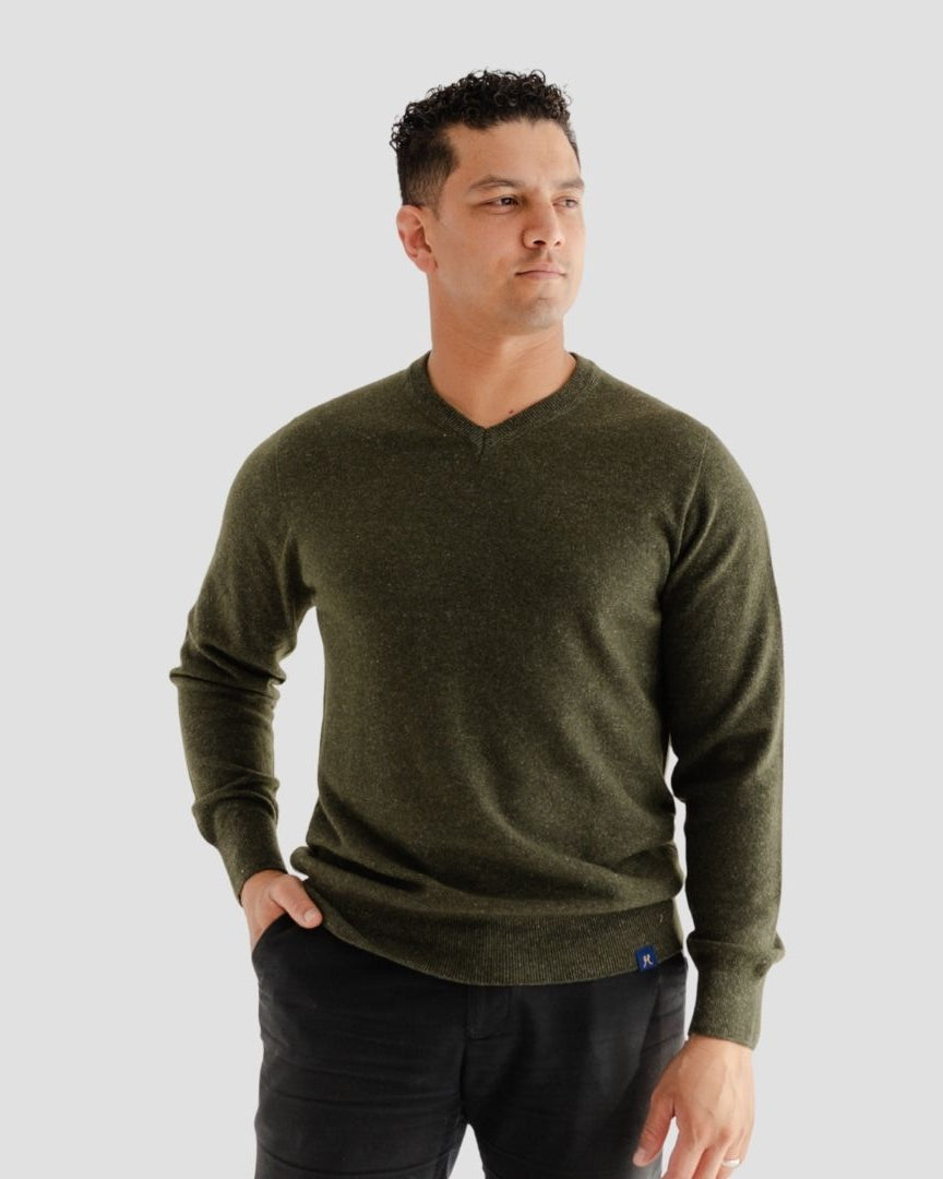 Man wearing a green sweater against a gray background