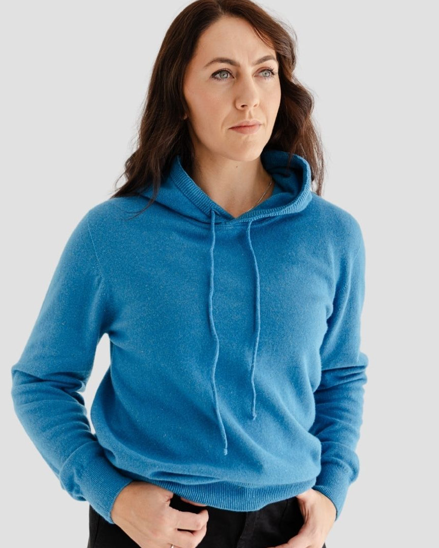 Woman wearing a blue hoodie against a plain background