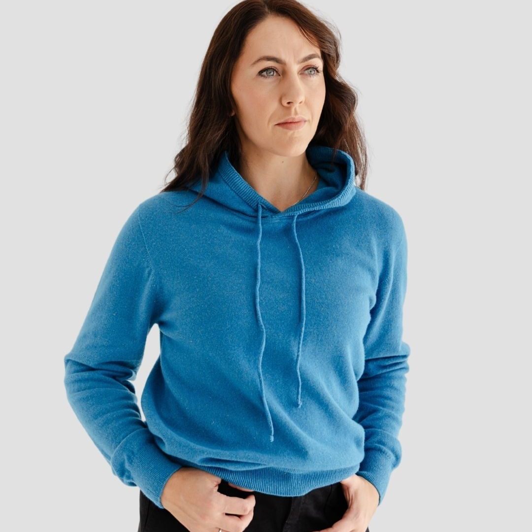 Woman wearing a blue hoodie against a plain background