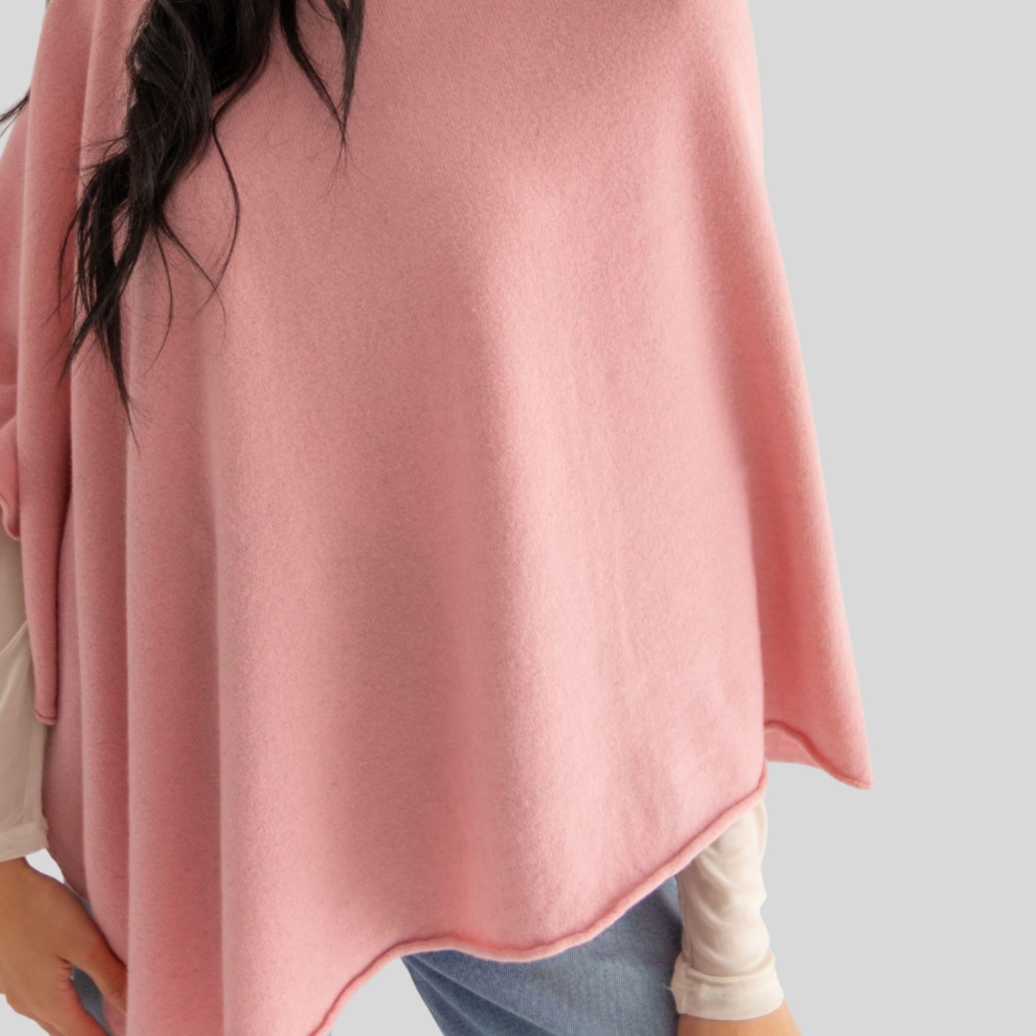 Person wearing a pink poncho on a plain background