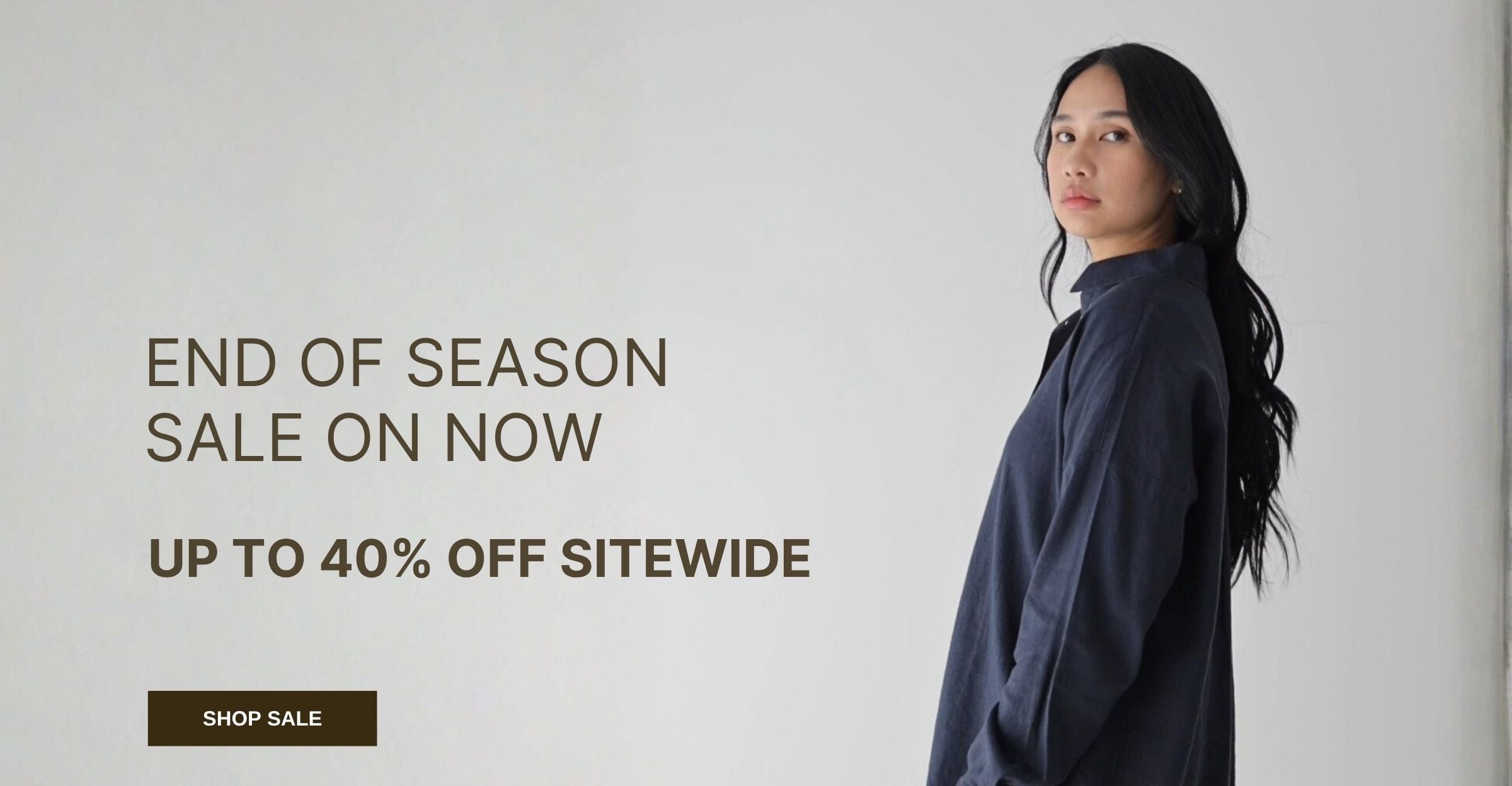 Woman wearing a dark blue shirt with promotional text for an end of season sale on a light gray background.