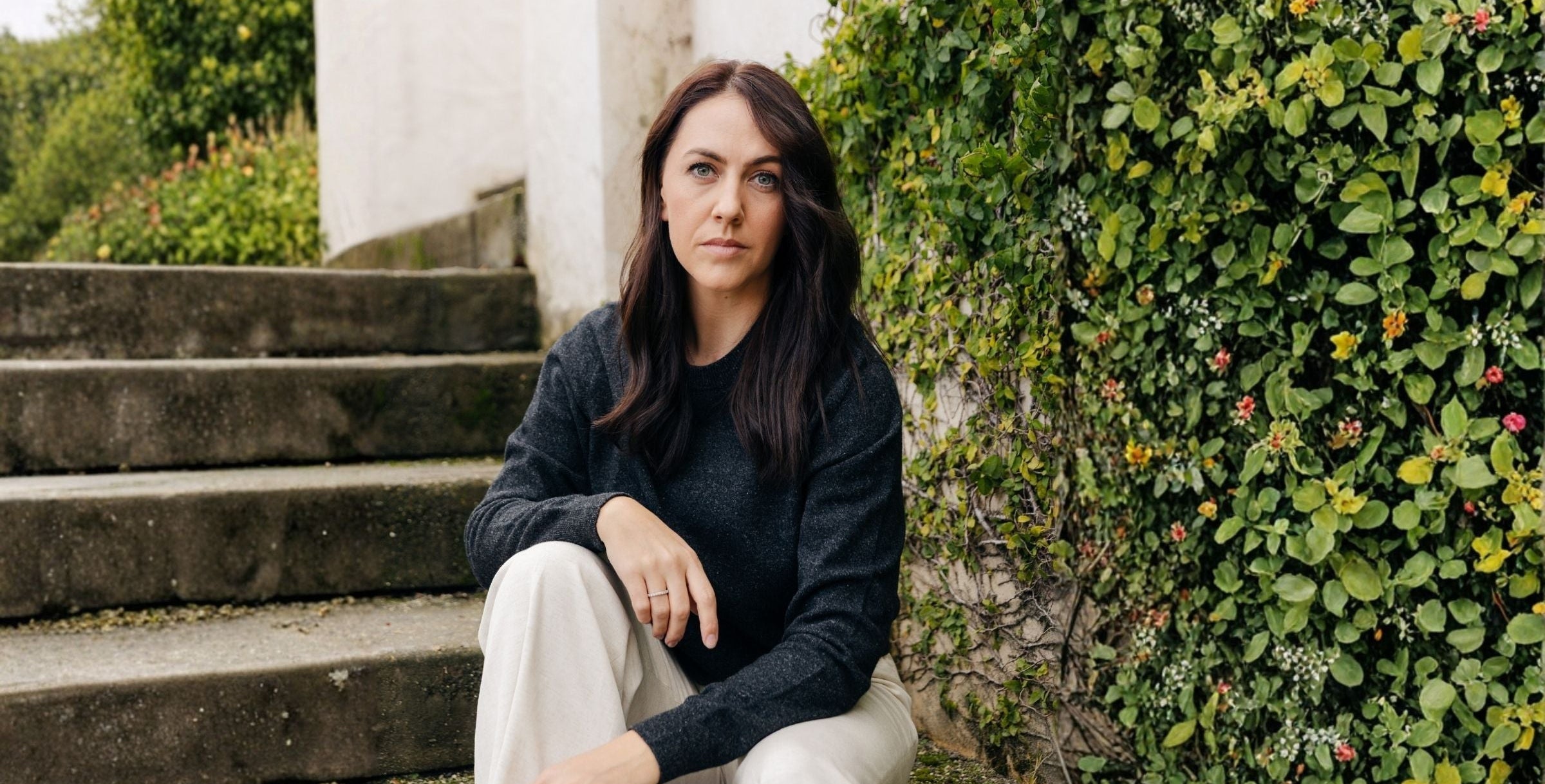 Woman sitting on steps in a garden setting