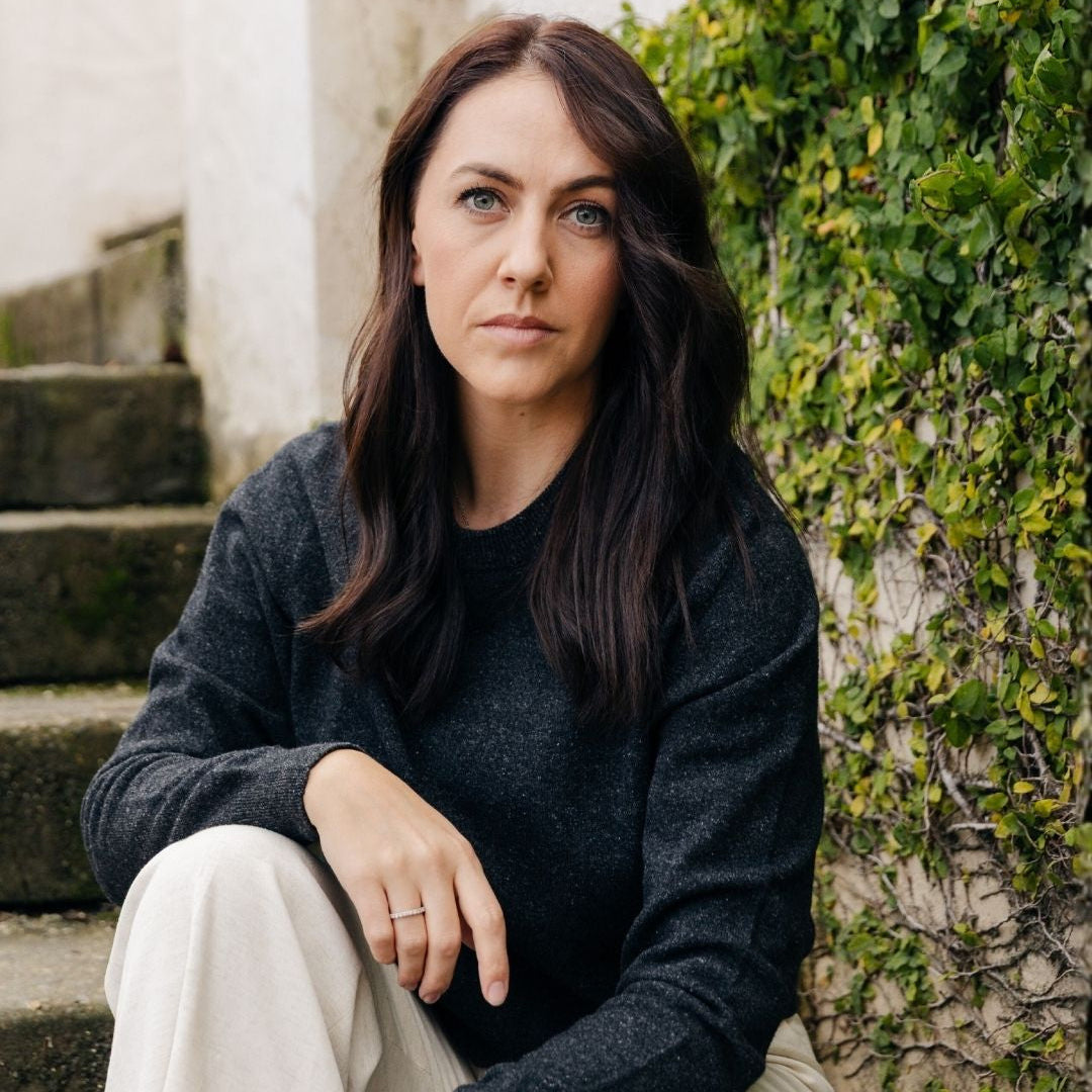 Woman sitting on steps with greenery in the background