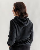Person wearing a dark gray hoodie on a plain background