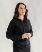 Woman wearing a dark gray hoodie against a plain background