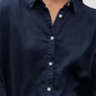 Person wearing a navy blue button-up shirt on a light gray background