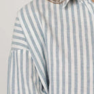 Striped shirt with blue and white vertical stripes on a light gray background