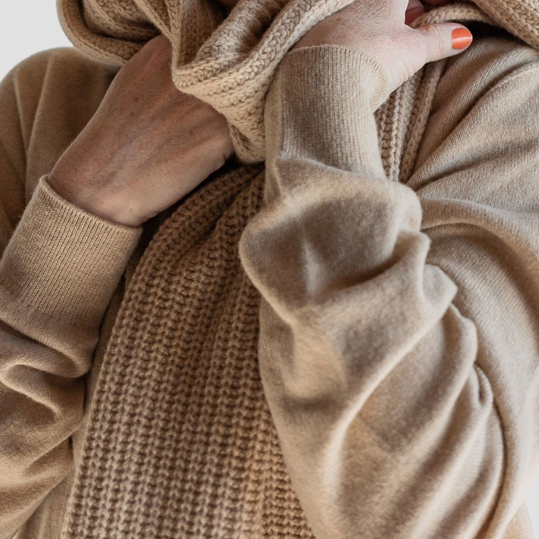 Close-up of a person wearing a beige sweater with a blurred background