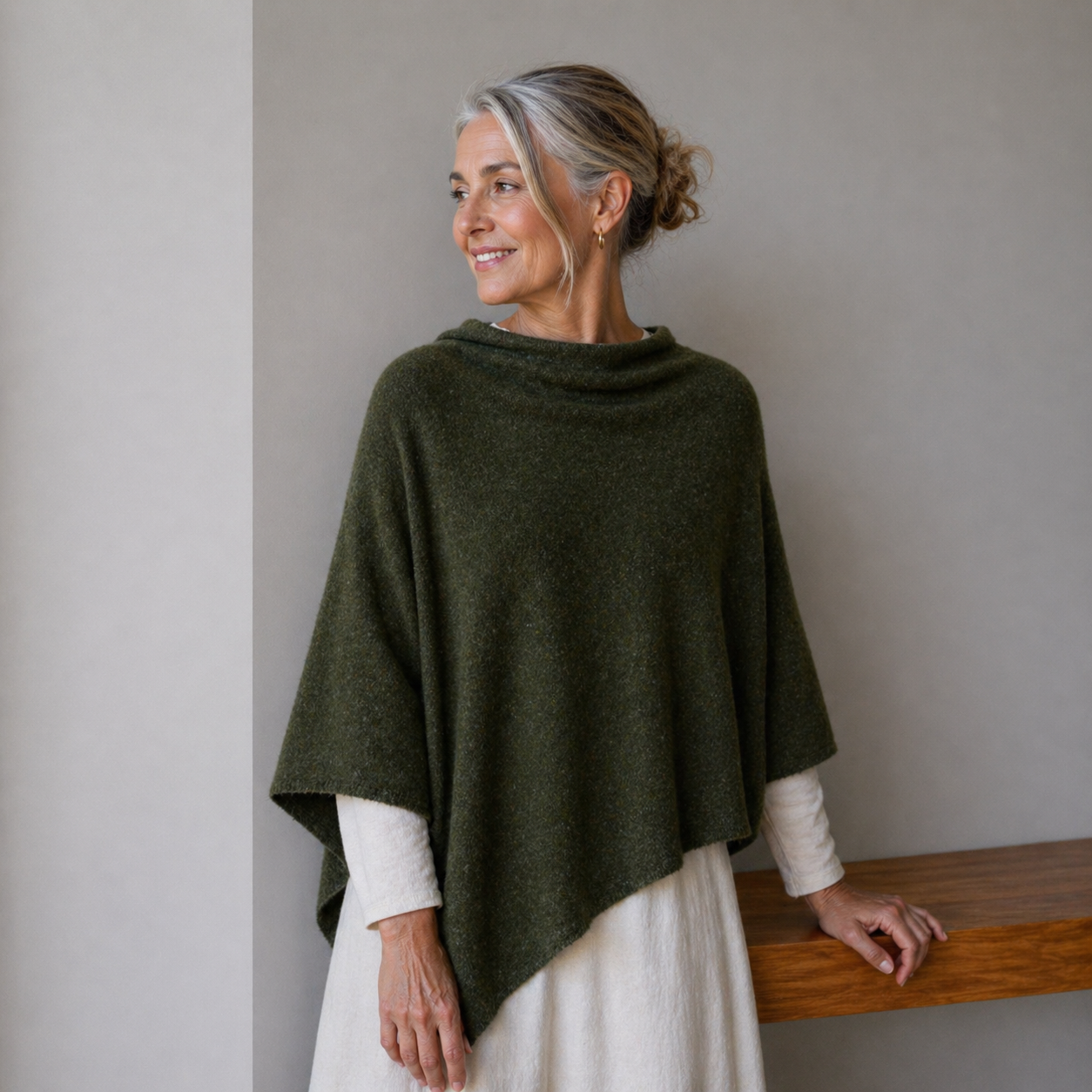 Woman wearing a green poncho against a plain background