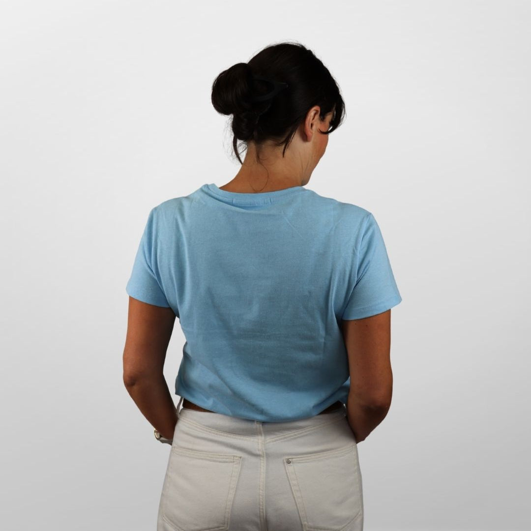 Person wearing a light blue t-shirt and beige pants against a white background