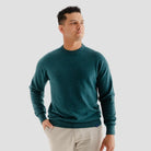 Man wearing a teal sweater against a plain background