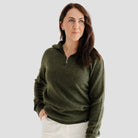 Woman wearing a green sweater against a plain background