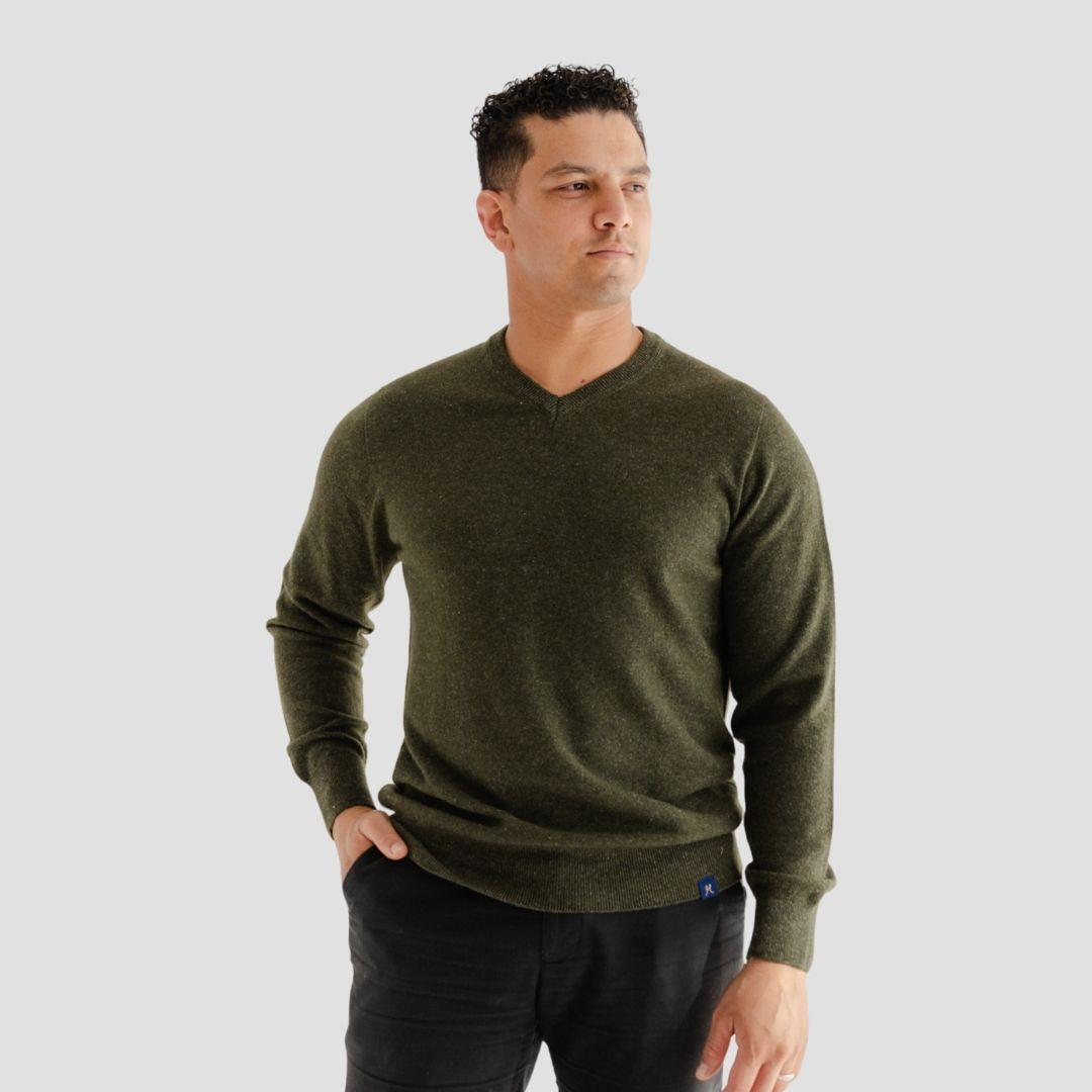 Man wearing a green sweater against a gray background