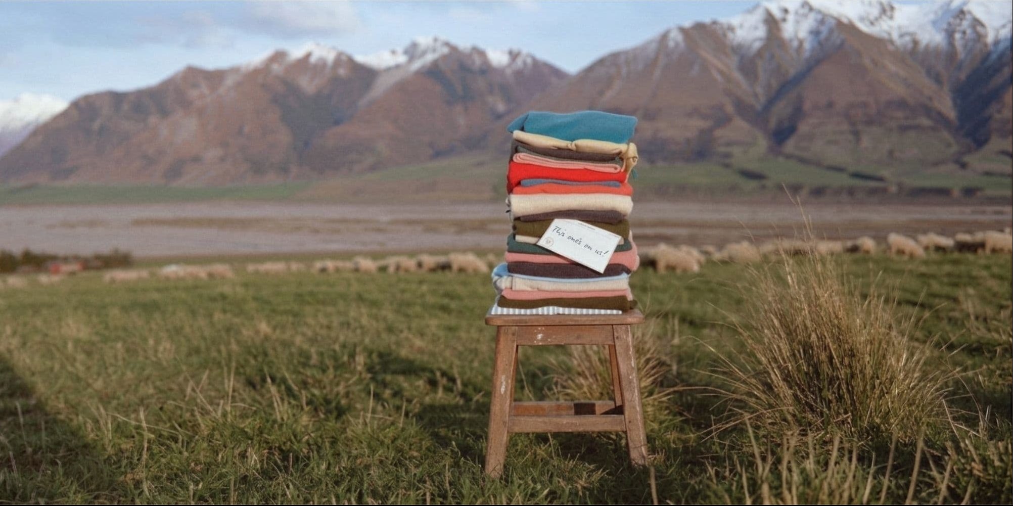 Chair with a colorful striped blanket in a field with mountains in the background